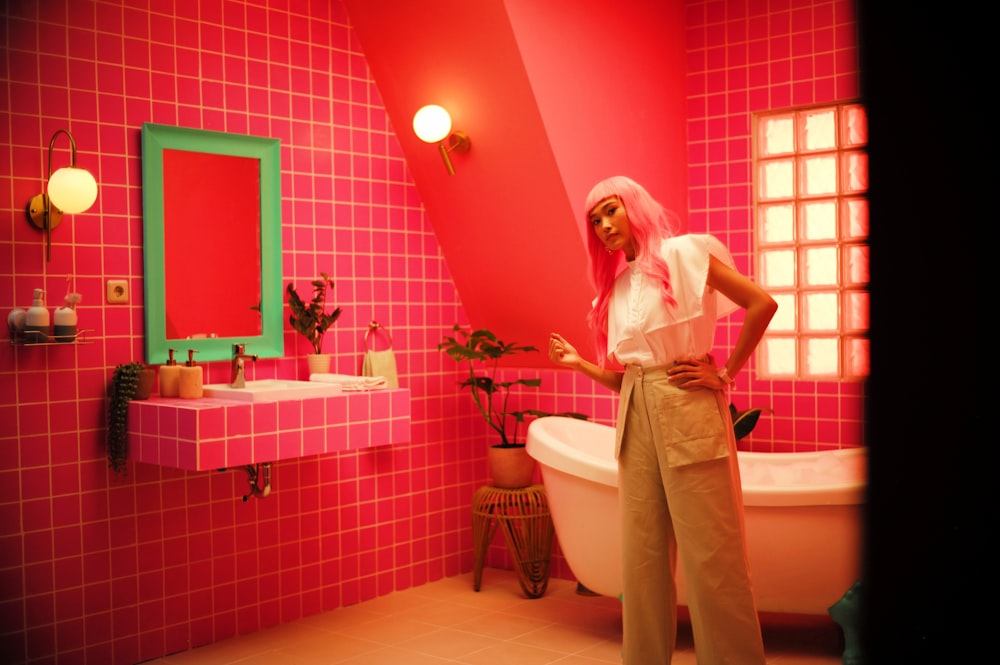 a woman standing in front of a pink bathroom