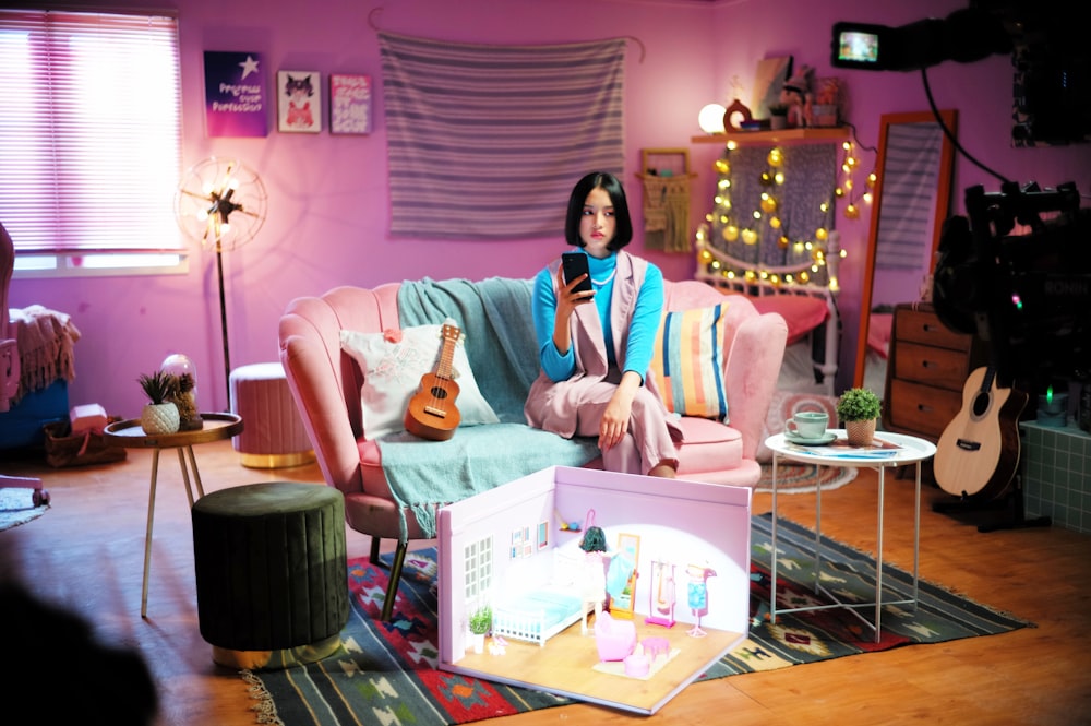 a woman sitting on a pink couch holding a cell phone