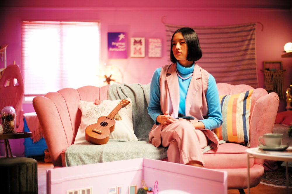 uma mulher sentada em um sofá com um violão