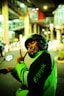 a man in a green jacket on a motorcycle giving the peace sign