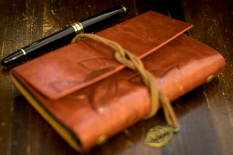 A brown leather notebook with a pen on top