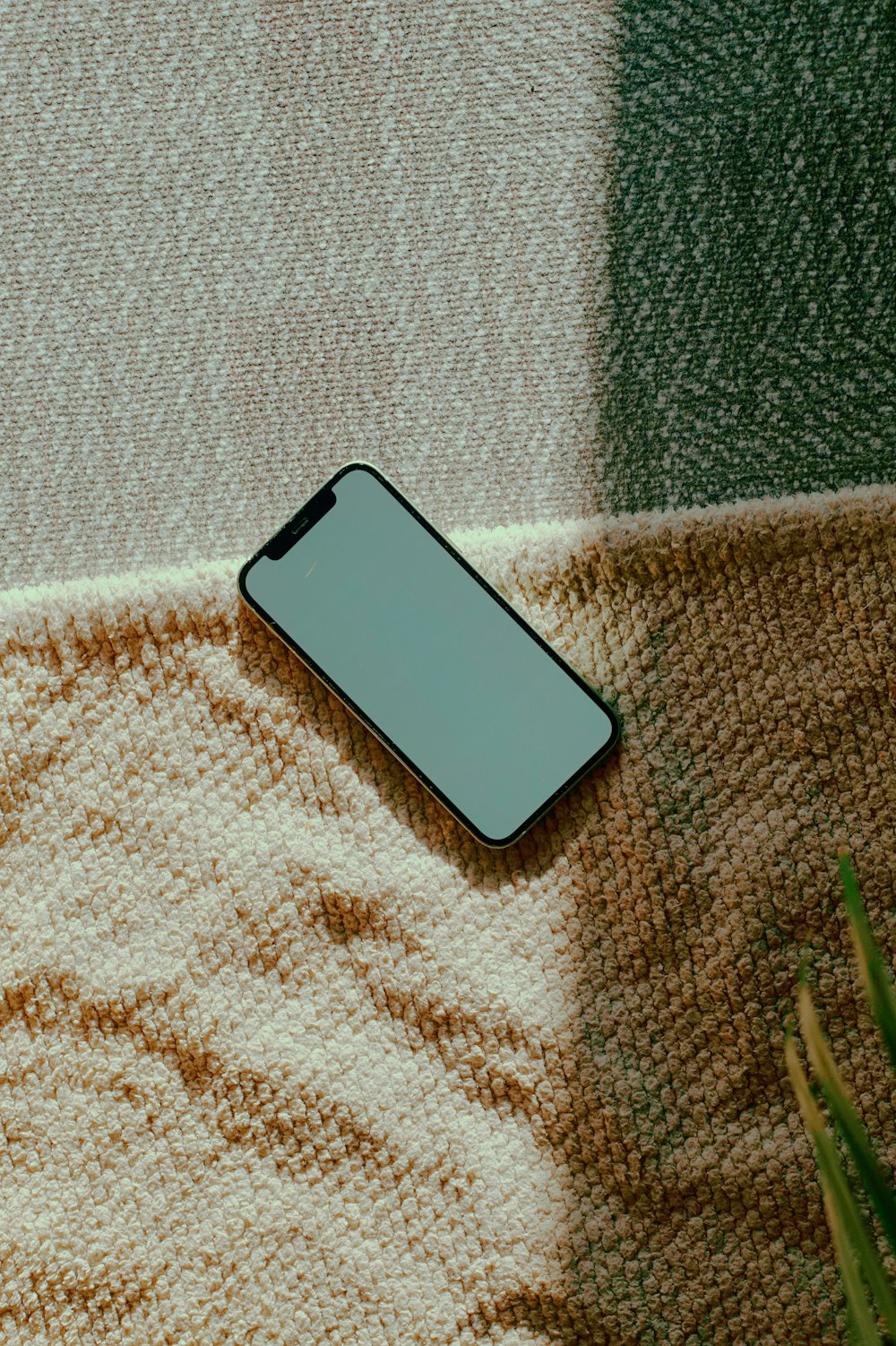 a cell phone sitting on top of a blanket next to a plant