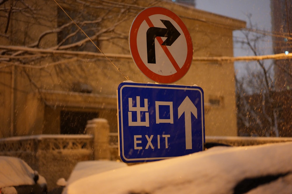 a blue street sign sitting on the side of a snow covered road