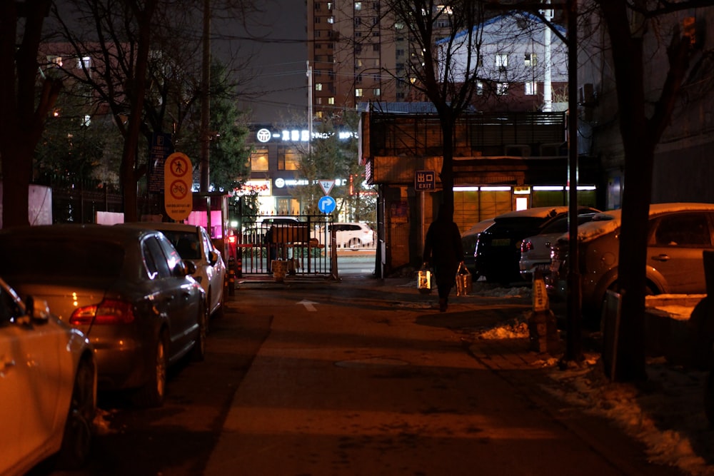 a city street at night with parked cars