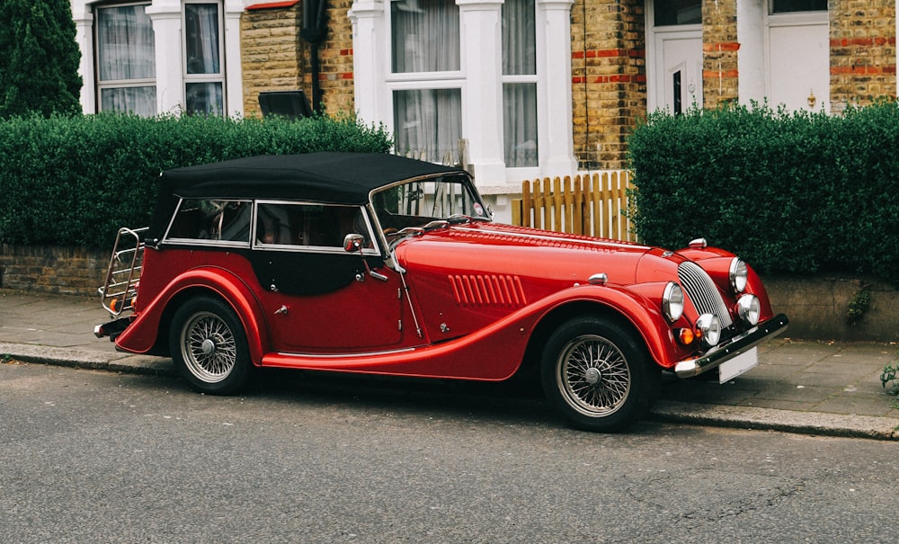 an old red car parked on the side of the road