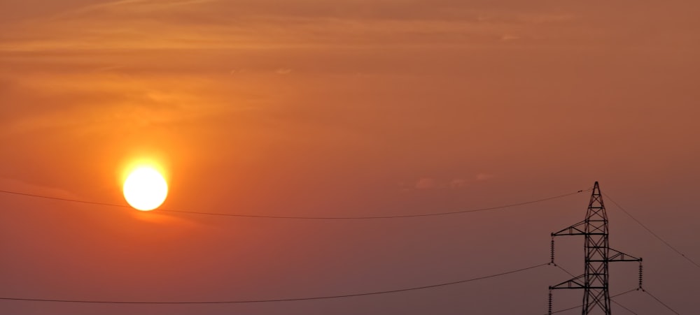 the sun is setting over a power line
