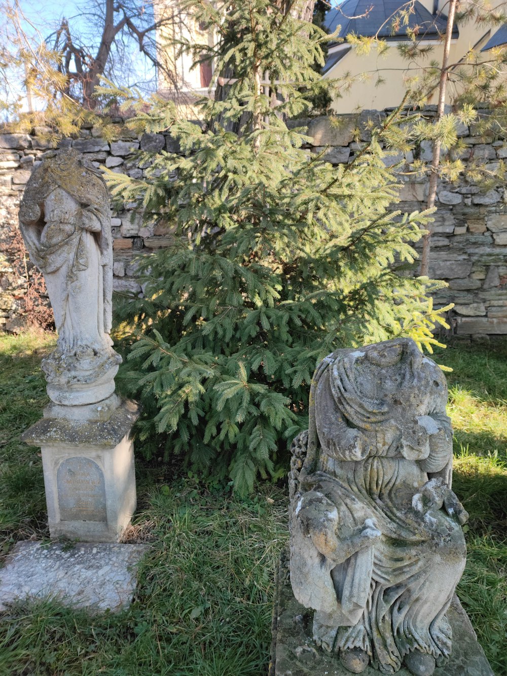 a stone statue sitting next to a tree