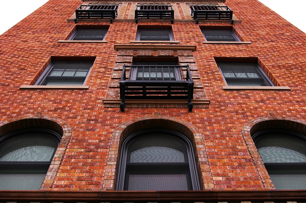 a tall brick building with windows and a balcony