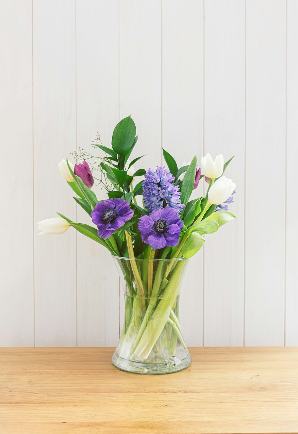 a glass vase filled with purple and white flowers