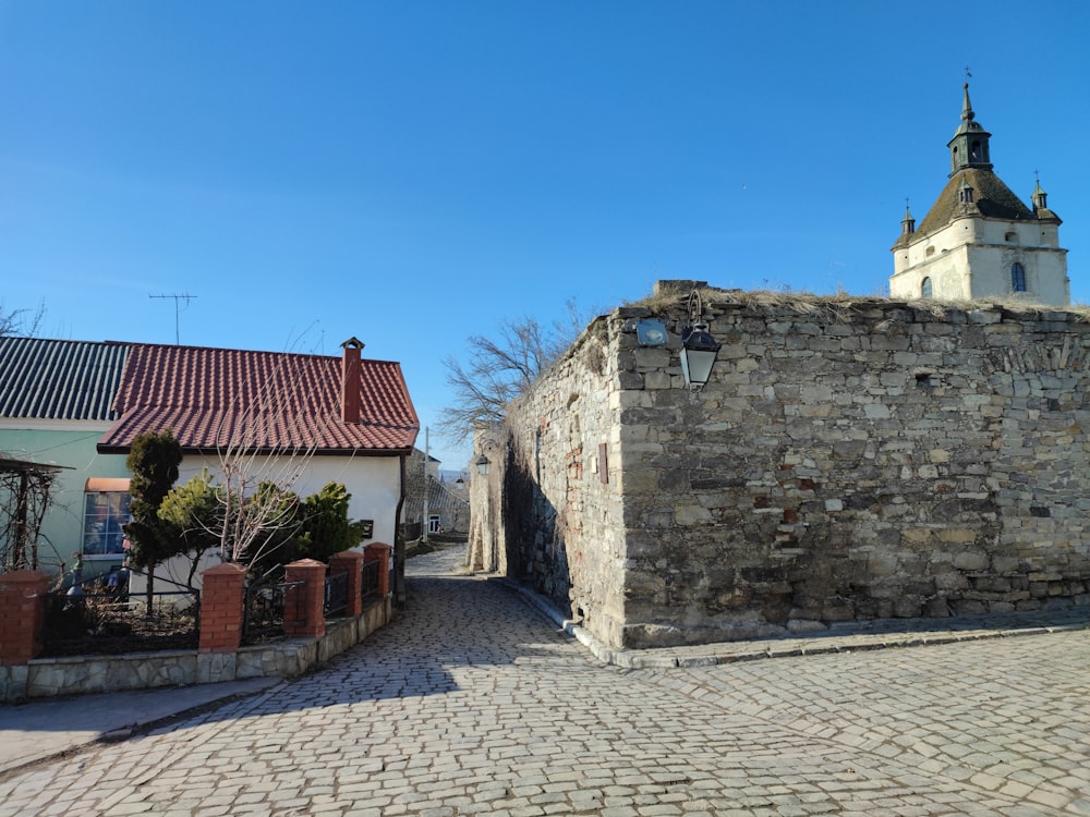 a cobblestone street with a church steeple in the background