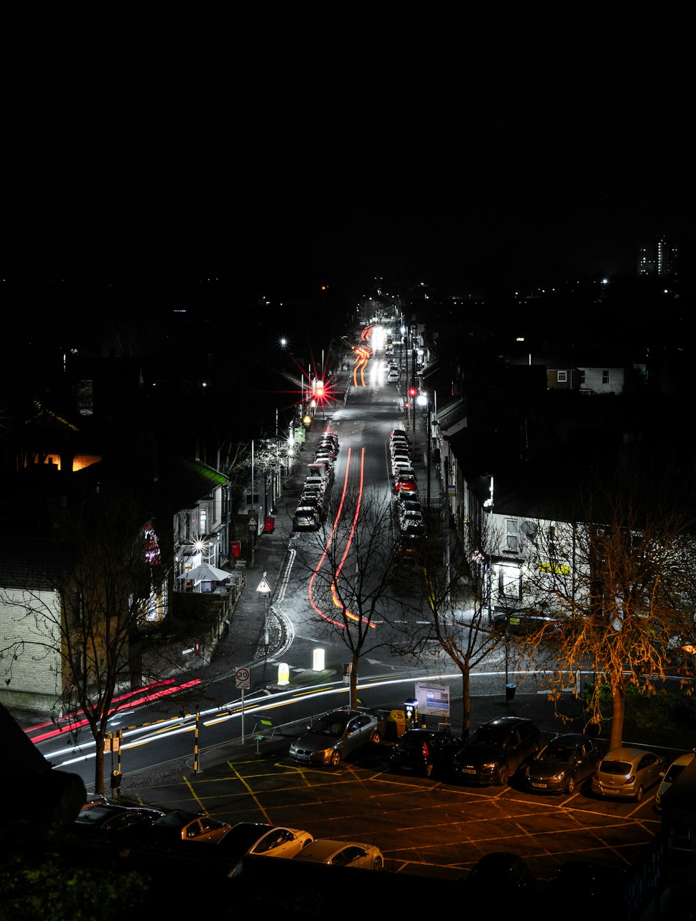 a city street at night with cars parked on the side of the road