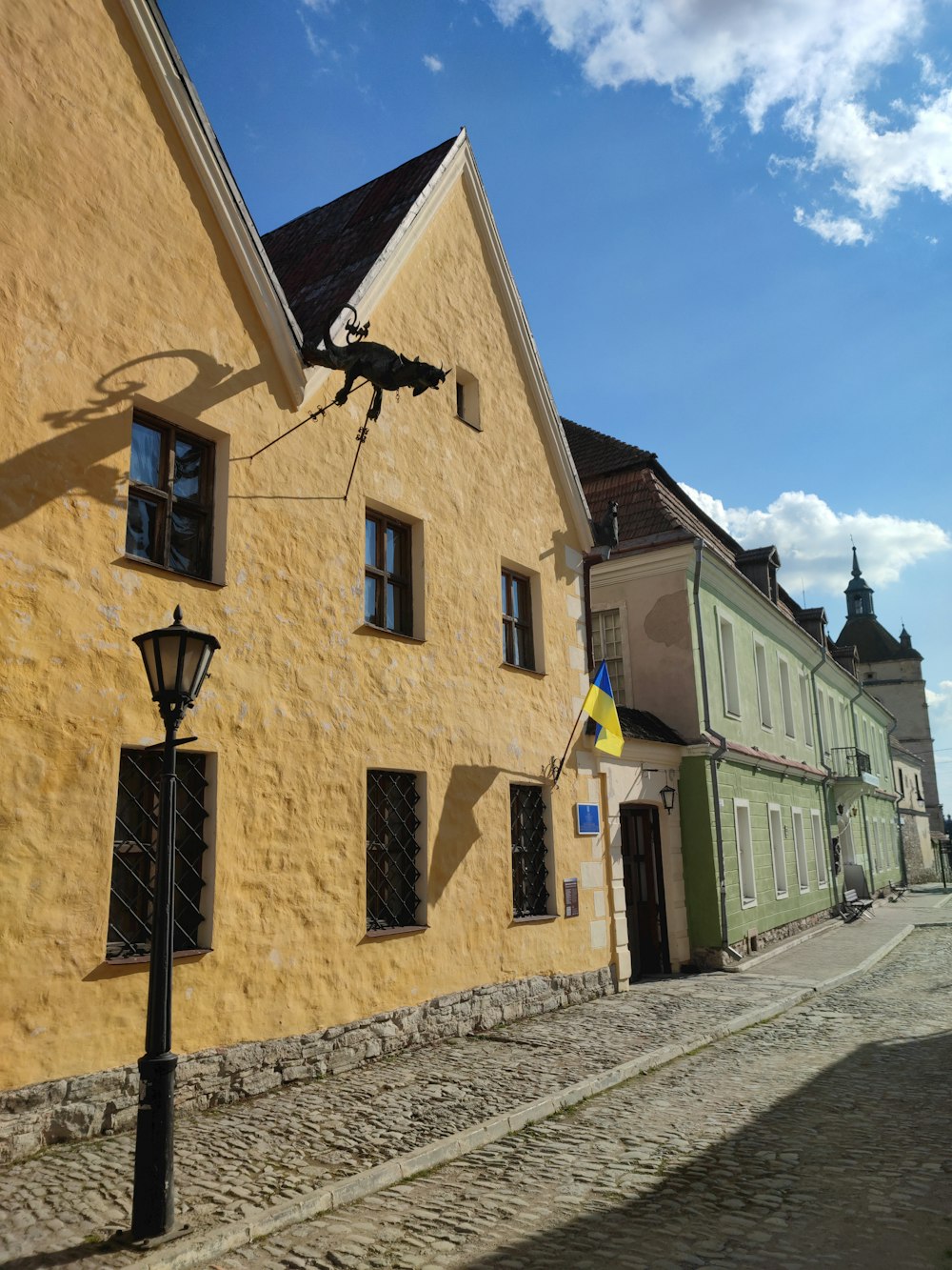 a yellow building with black shutters on a cobblestone street