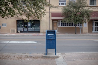 a blue mailbox sitting on the side of a road