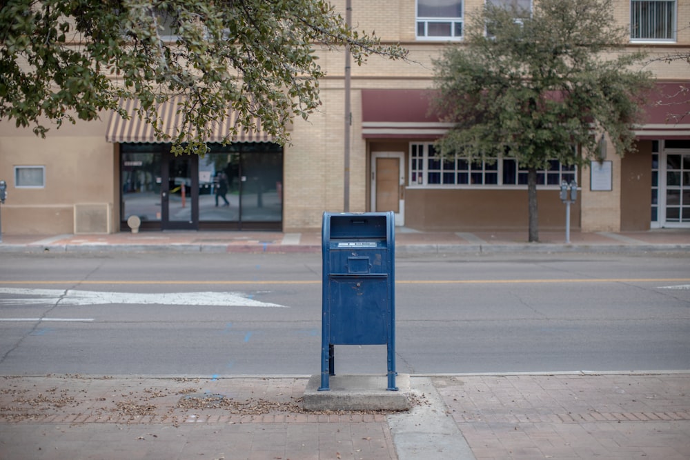 a blue mailbox sitting on the side of a road