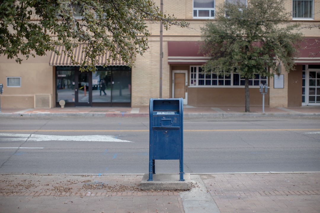 a blue mailbox sitting on the side of a road, Blue USPS mail box on a sidewalk
