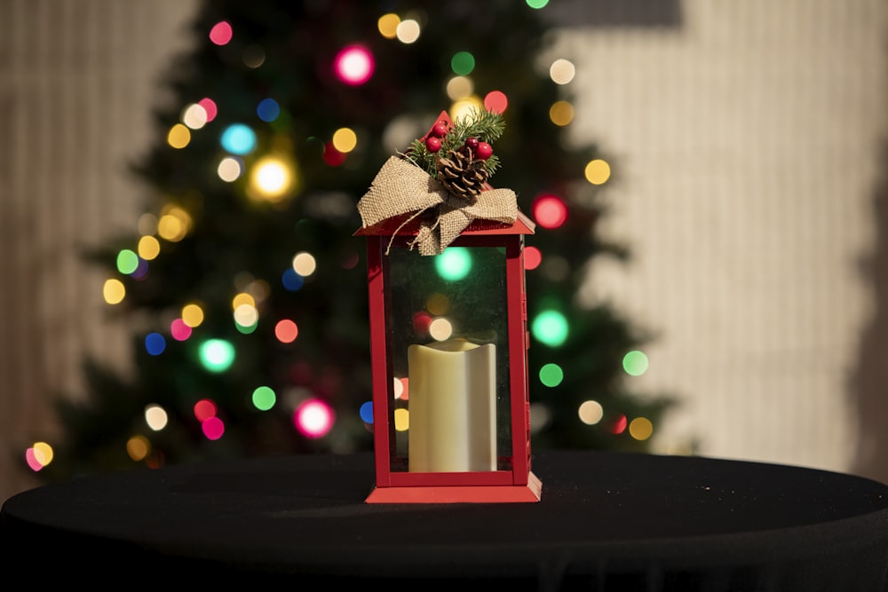 a red lantern on a table with a christmas tree in the background