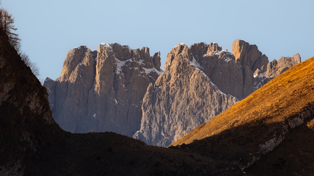 the mountains are covered in snow and brown grass