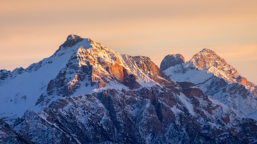 a mountain range covered in snow at sunset