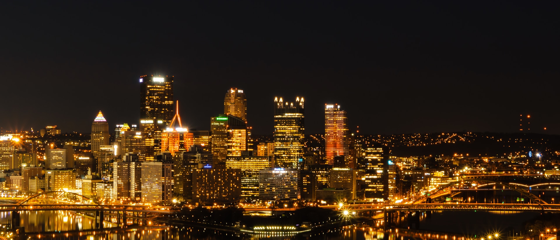 a city at night with a bridge and a bridge in the foreground