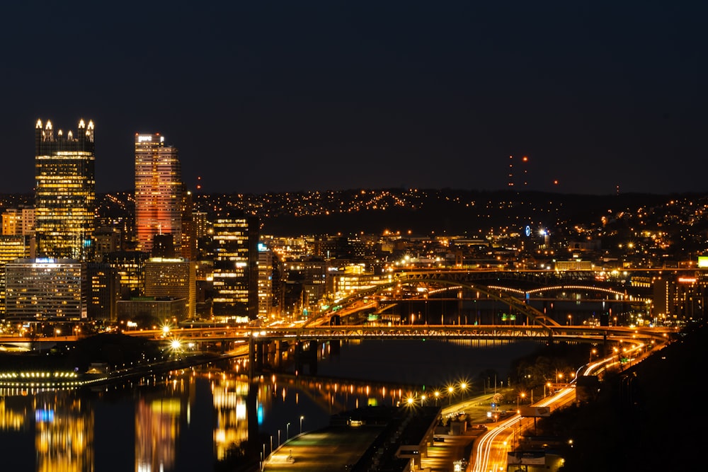 uma vista de uma cidade à noite com uma ponte em primeiro plano