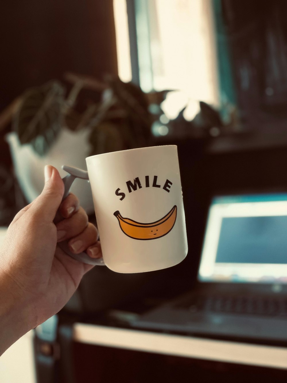 a person holding a coffee mug with a smile on it