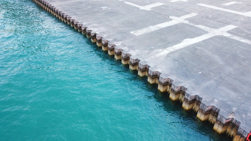 a man standing on a dock next to a body of water