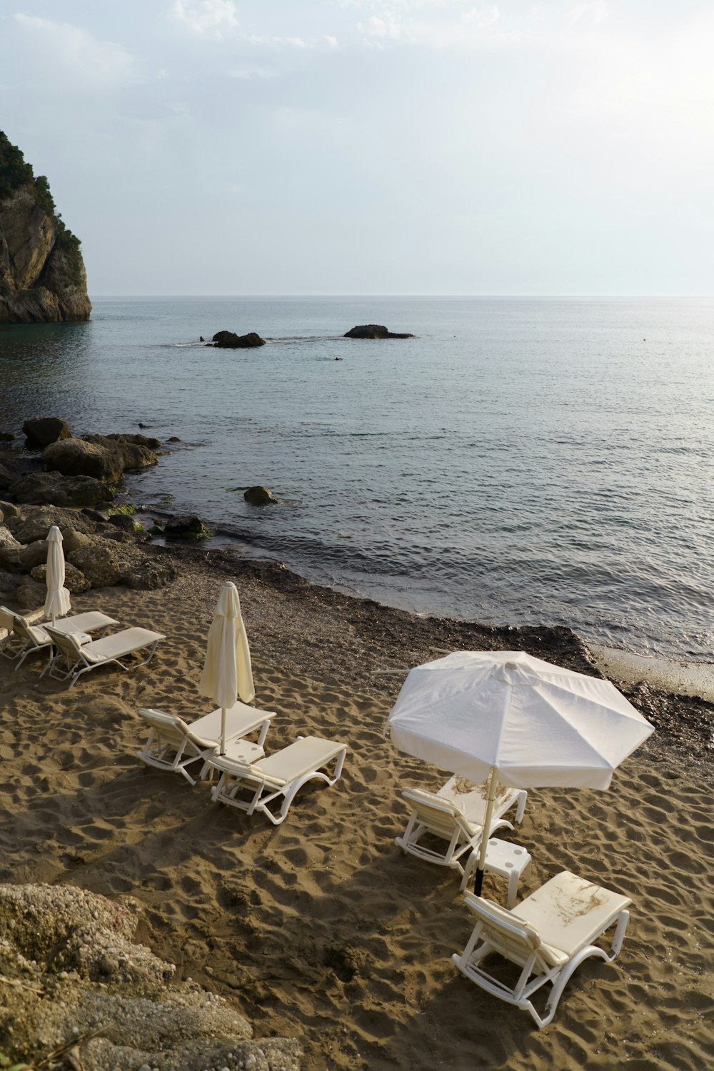 a couple of lawn chairs sitting on top of a sandy beach