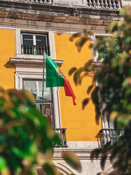 a flag flying in front of a yellow building