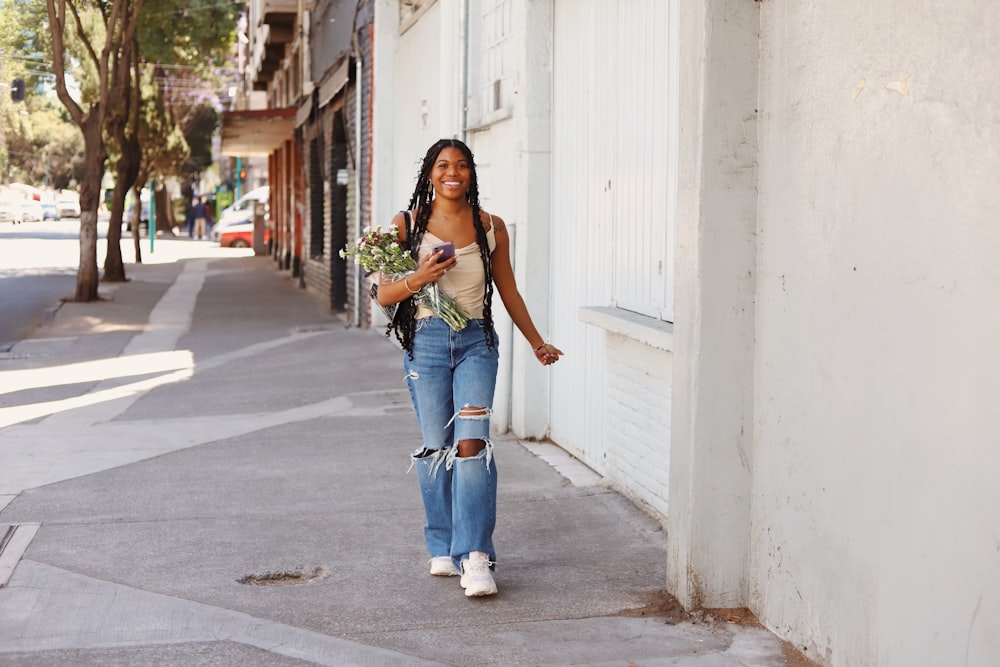 a woman walking down a street holding a bouquet of flowers