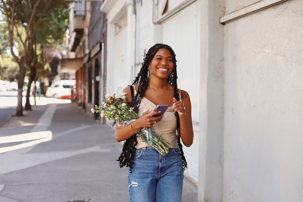 a woman walking down a street holding a bouquet of flowers