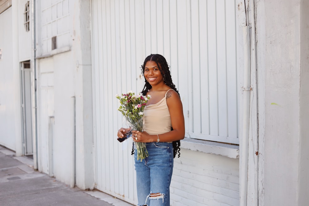 a woman holding a bunch of flowers standing in front of a building