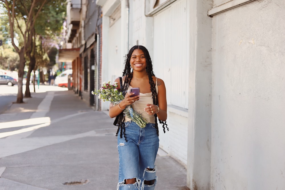 a woman walking down a street holding a bouquet of flowers