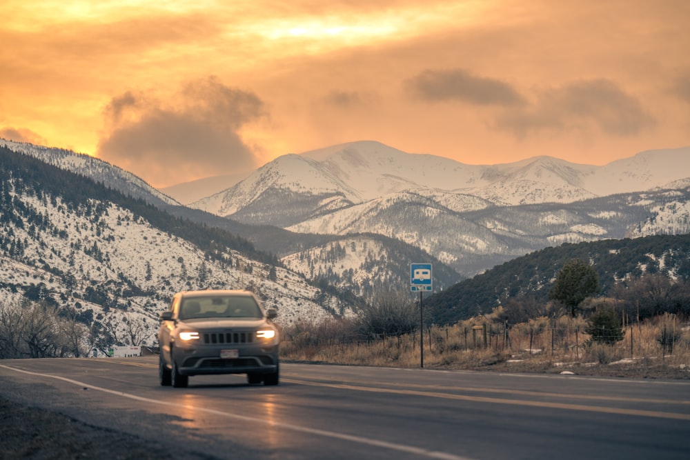 a jeep driving down a road with mountains in the background