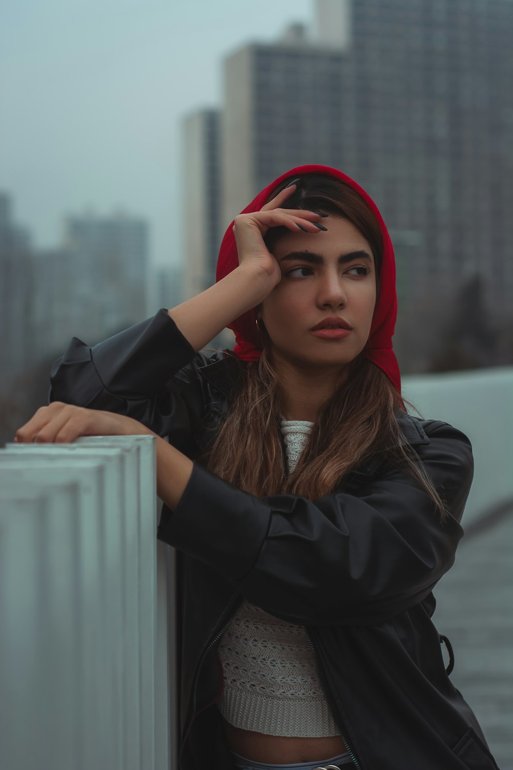 a woman leaning against a wall wearing a red hoodie