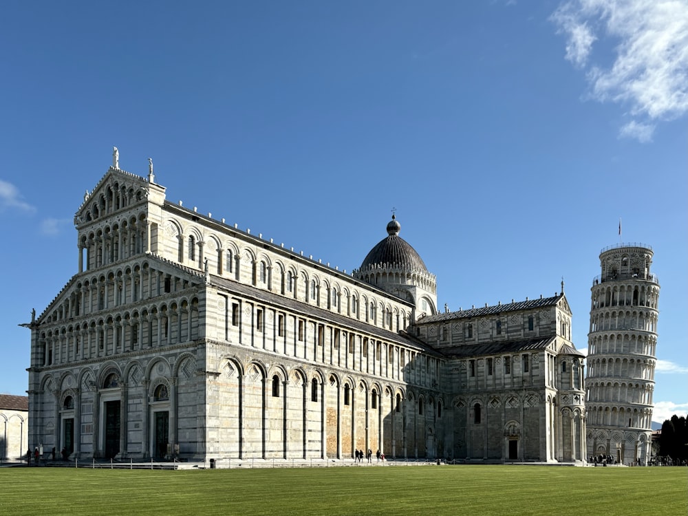 a large building with a tall tower next to a green field