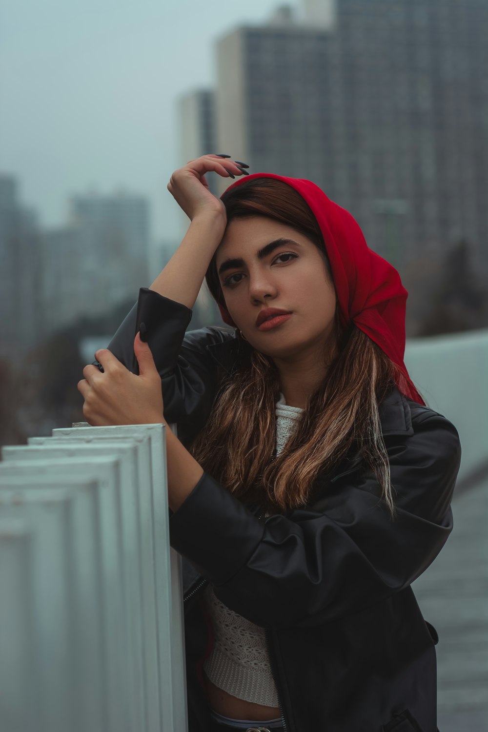 a woman with a red hoodie leaning against a wall