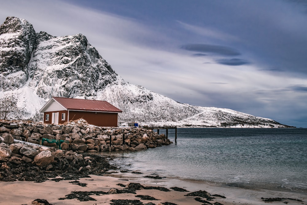 a house on the shore of a lake with a mountain in the background