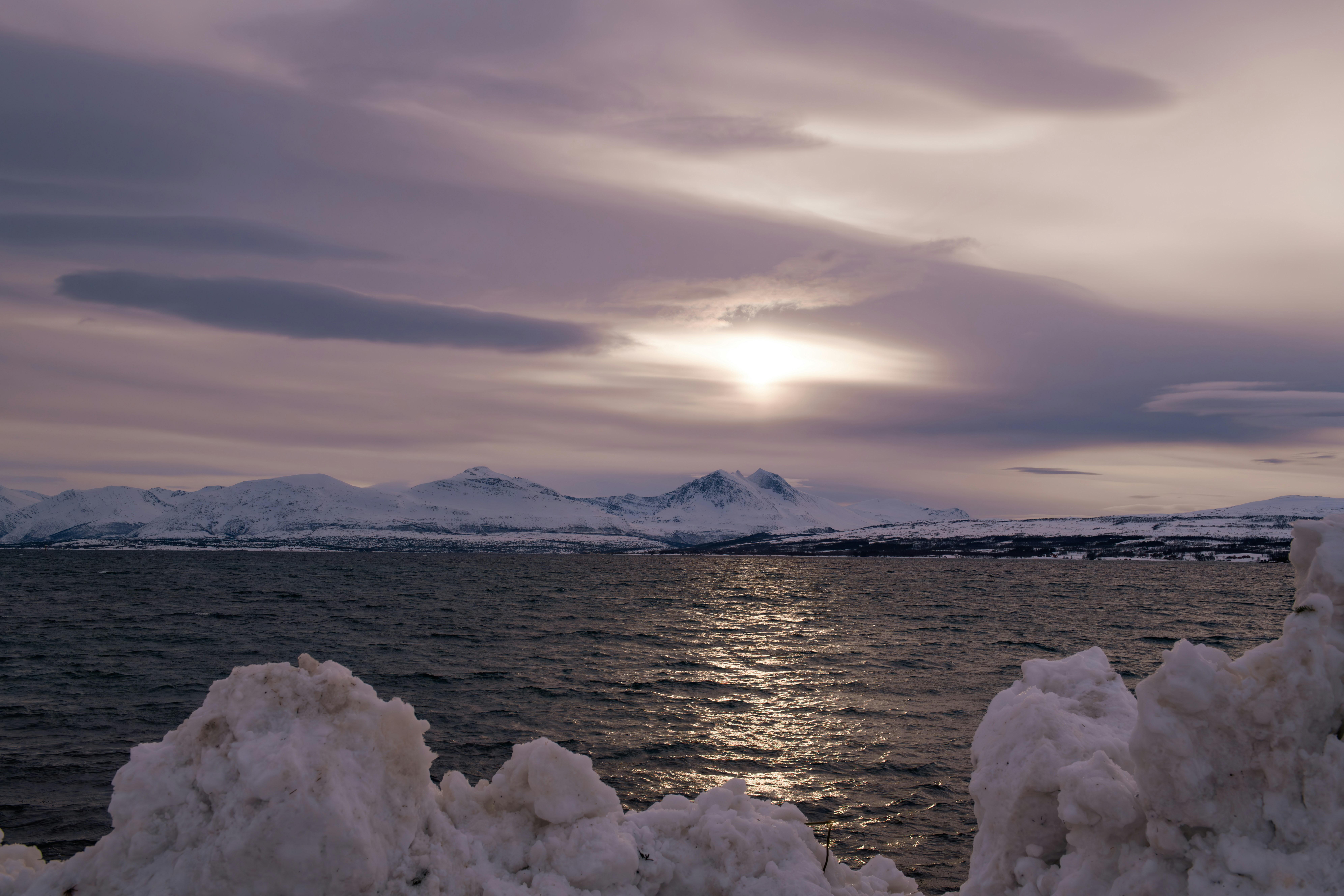 a body of water surrounded by snow covered mountains