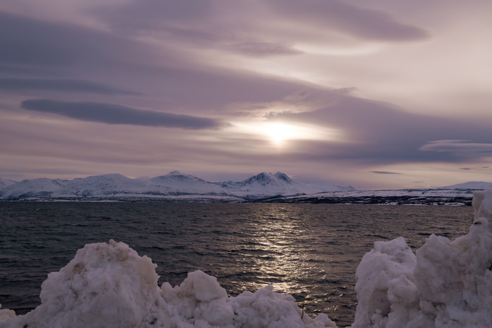 a body of water surrounded by snow covered mountains