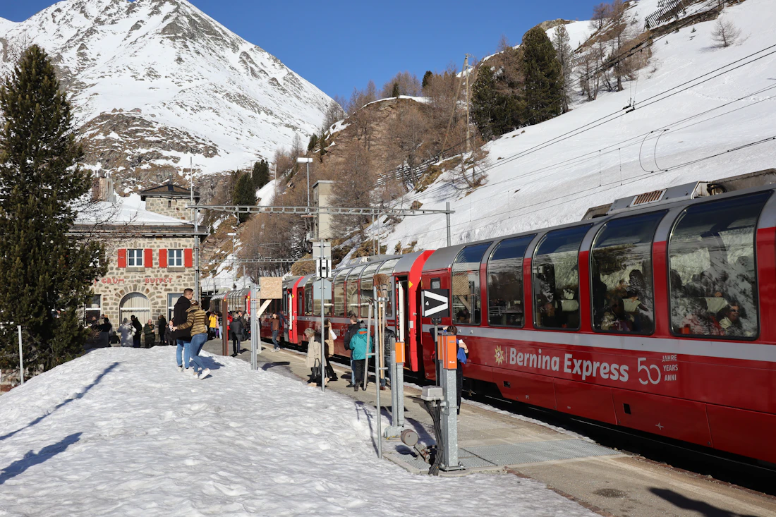 The red Bernina Express train crossing a snowy alpine village in winter