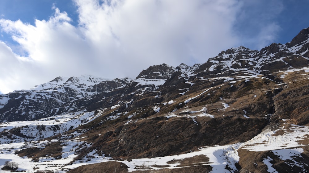 a mountain covered in snow under a cloudy blue sky