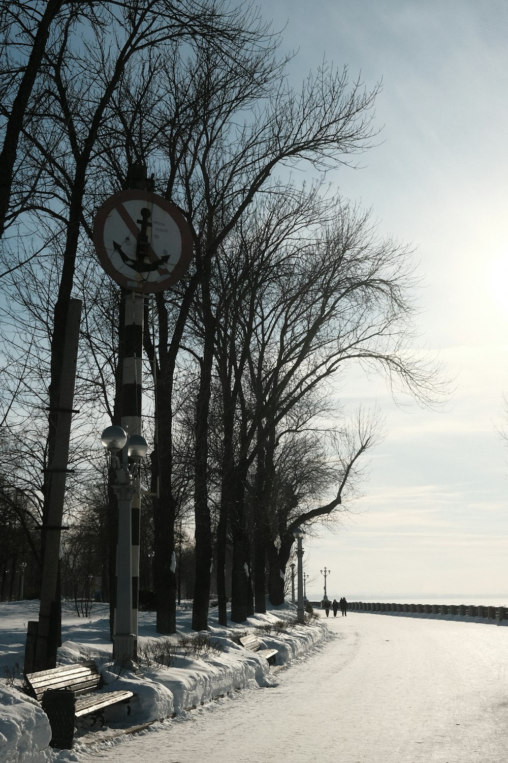 a snowy road with benches and a street sign