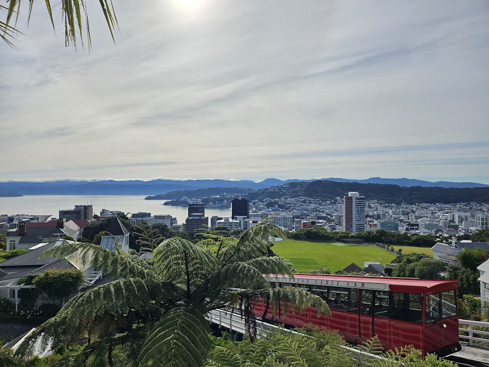 a red train traveling down tracks next to a lush green hillside