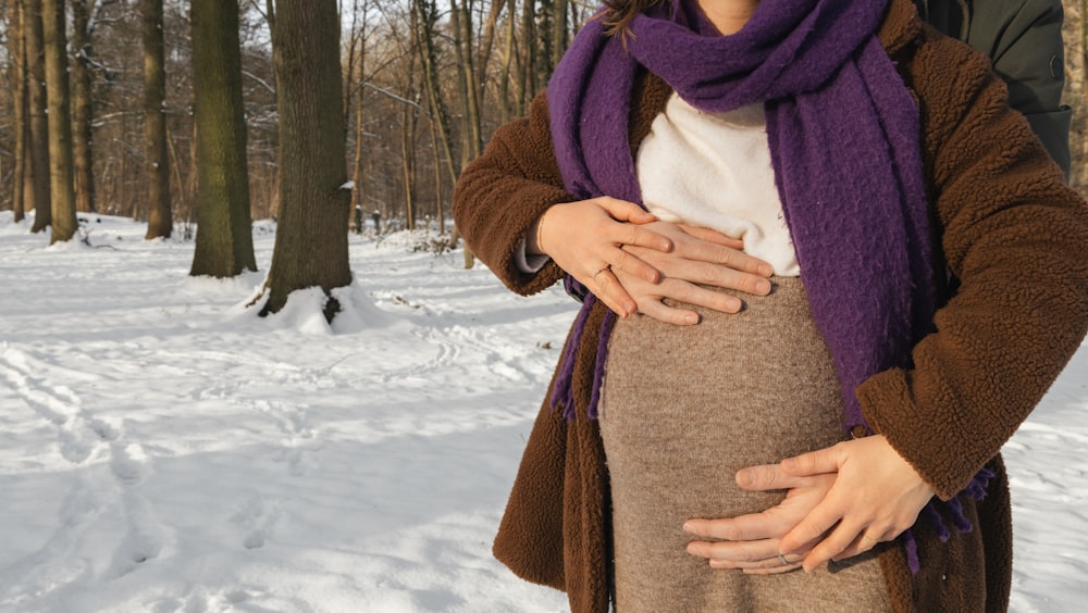 a woman standing in the snow holding her stomach