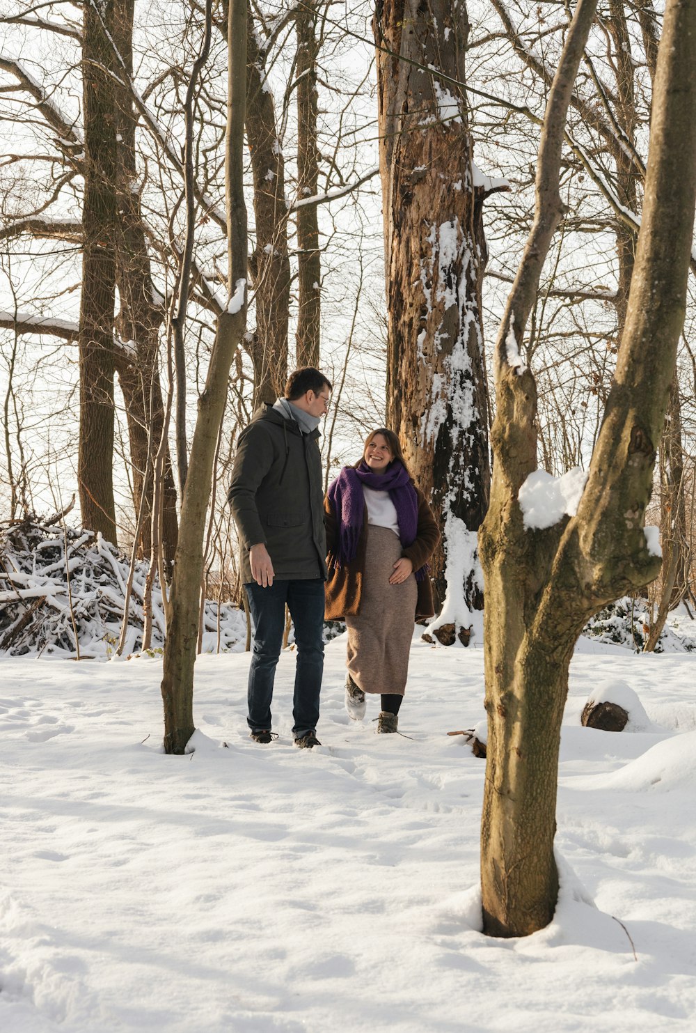 a man and a woman walking through a snowy forest
