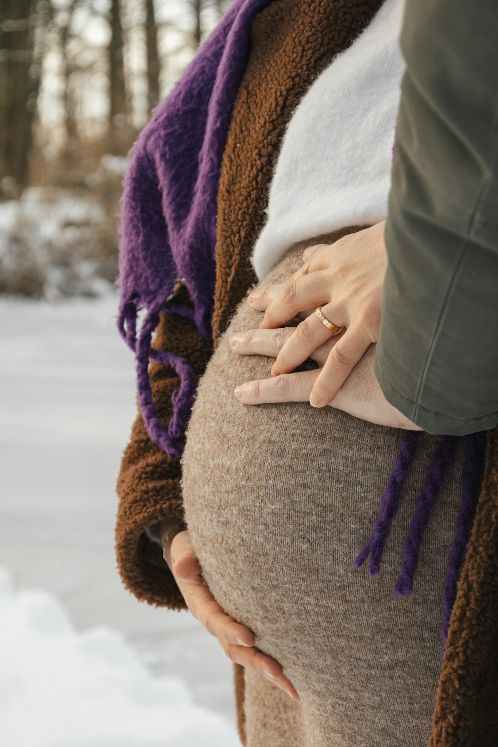 a pregnant woman is holding her belly in the snow