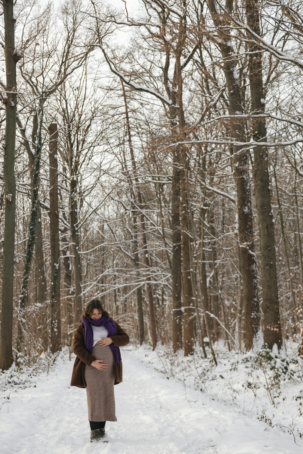 a pregnant woman walking through a snowy forest