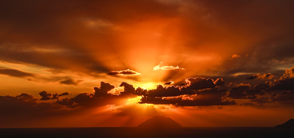 o sol está se pondo sobre uma montanha com nuvens