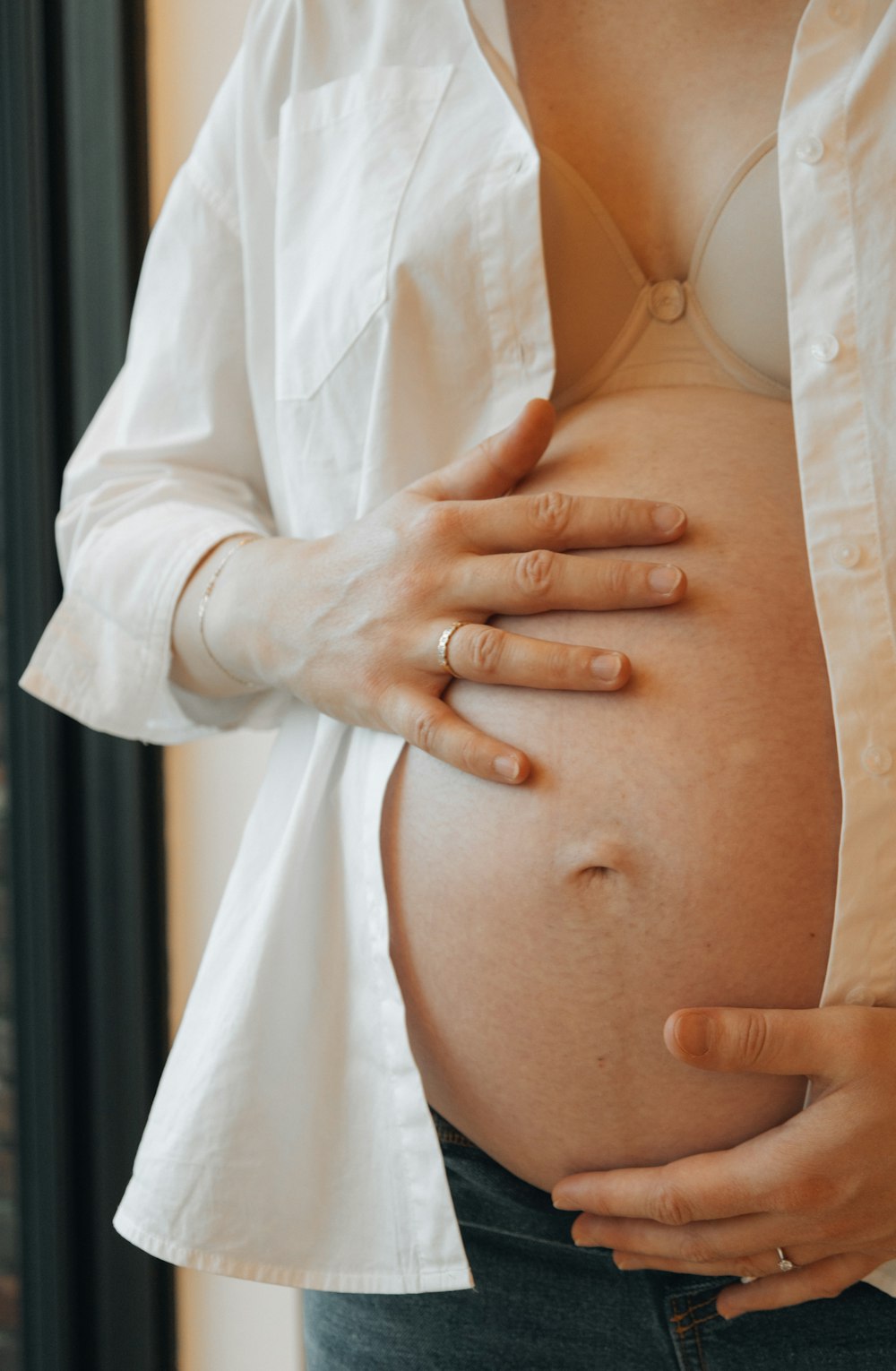 eine schwangere Frau mit den Händen auf dem Bauch