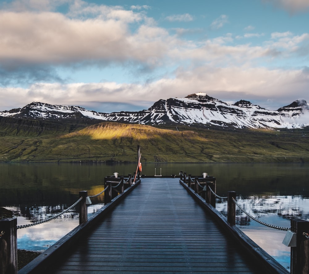 a wooden dock with mountains in the background